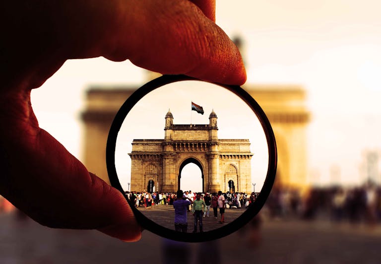 Person Holding Round Glasses in Shallow Photo